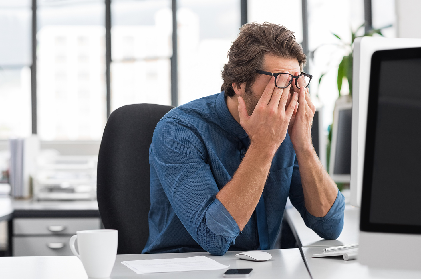 Person rubbing face in front of computer